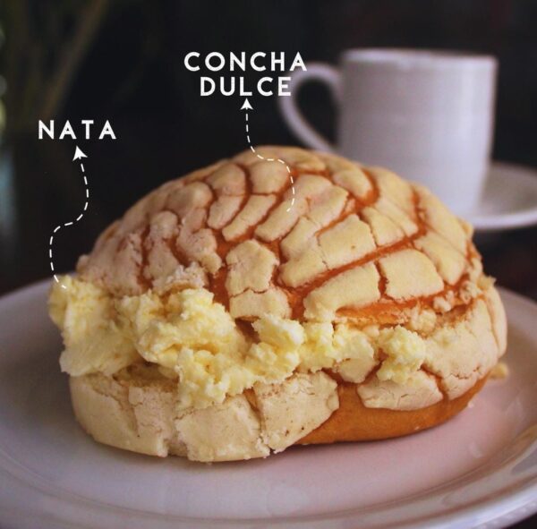 Frasco de vidrio lleno de Nata fresca y espesa, con una cuchara de madera.