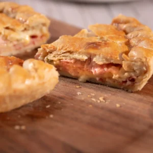 Rebanada de pay salado mostrando el relleno de queso derretido y jamón
