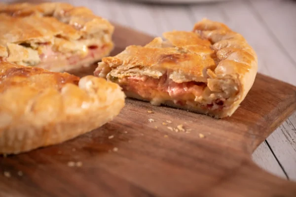 Rebanada de pay salado mostrando el relleno de queso derretido y jamón