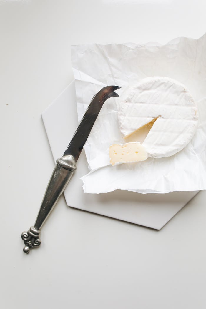 why-choose-us Elegant still life of sliced Brie cheese with a vintage knife on a white background.
