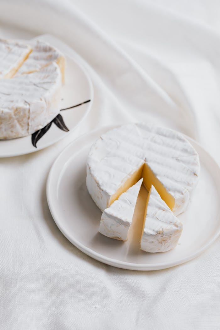 Tasty brie cheese slices on white ceramic plates with elegant arrangements.