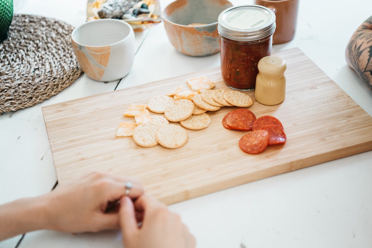 digital Snack selection with crackers, cheese, and pepperoni on a wooden board.