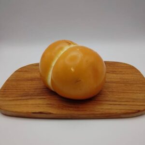 Pieza de queso ahumado con su caracteristica corteza oscura sobre table rustica