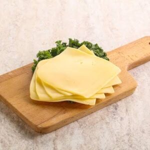 Rueda de Queso Manchego junto a varias rebanadas del mismo queso.